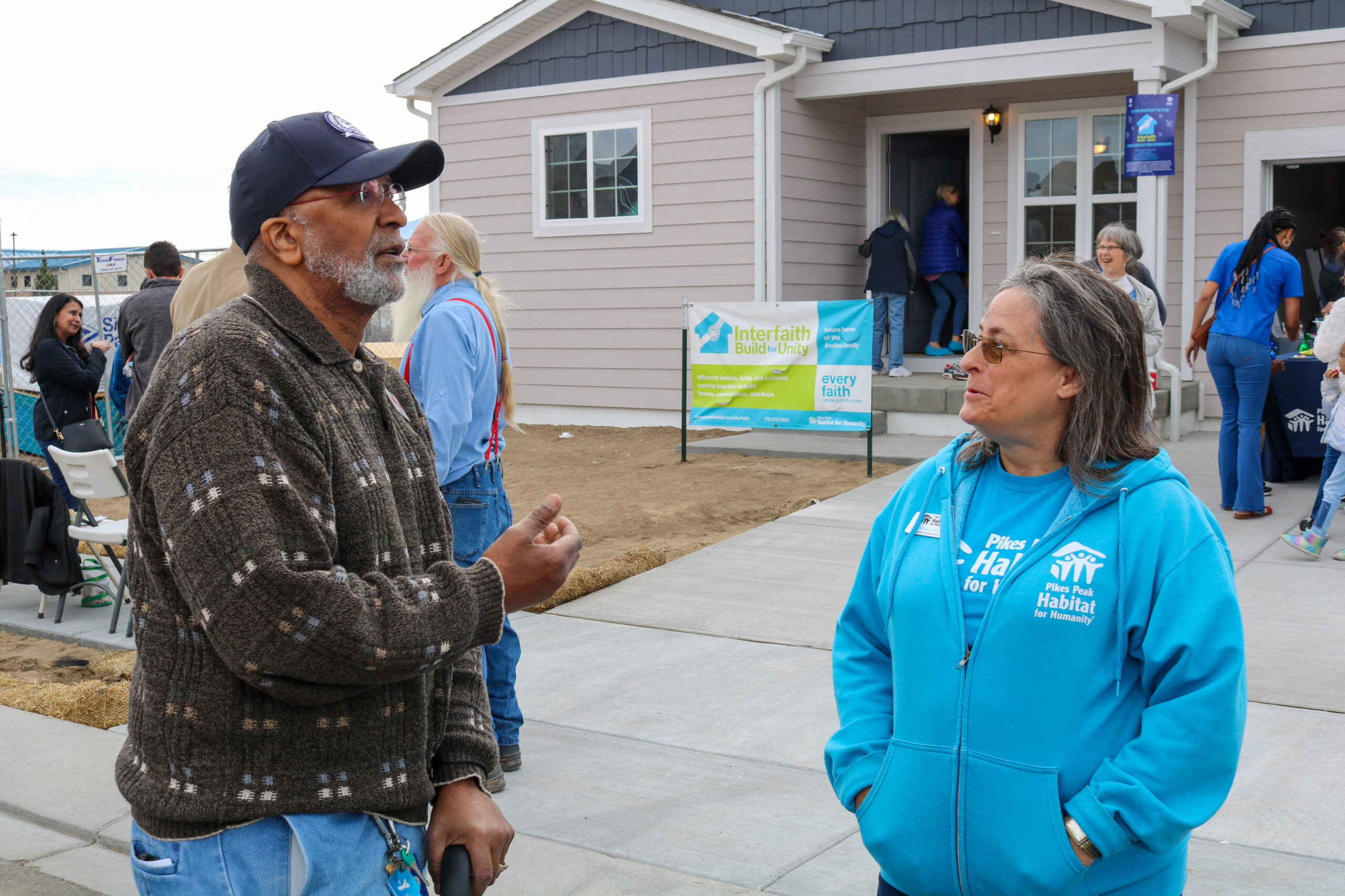 Two people speaking in front of Habitat home