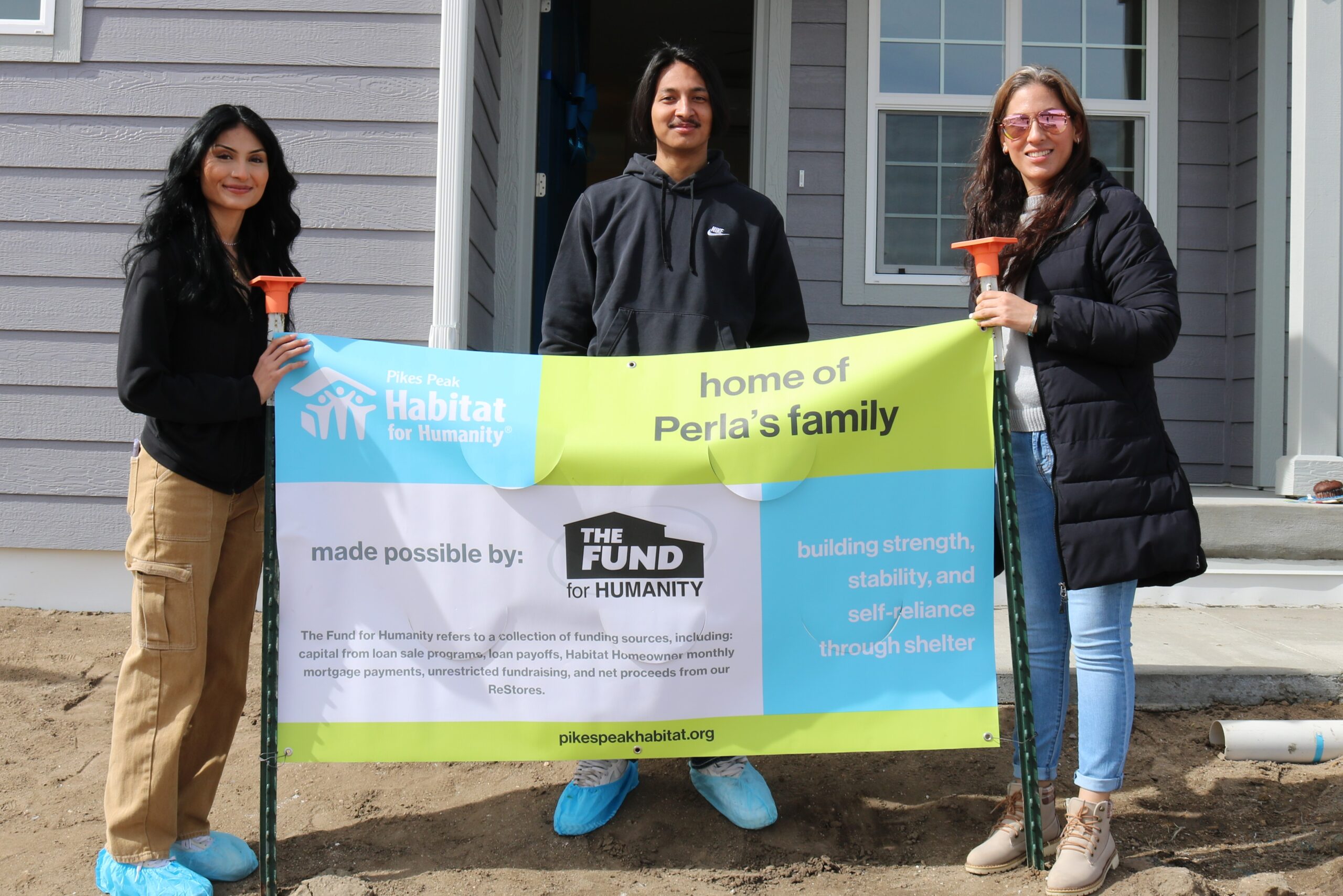 Perla and her children with their home banner