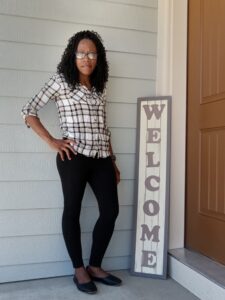 Woman standing by Welcome sign at her front door