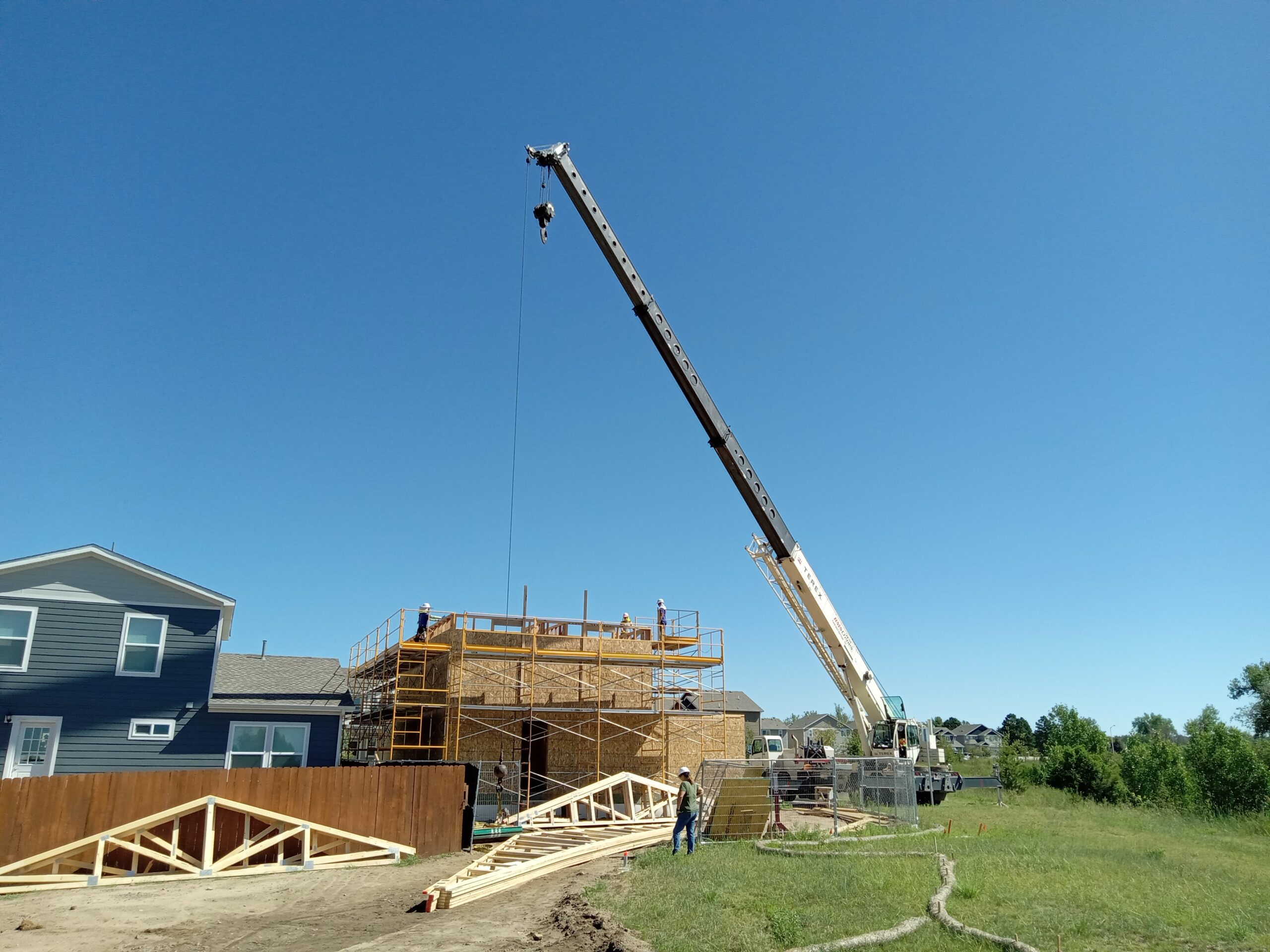 Crane raising tresses on two-story home.
