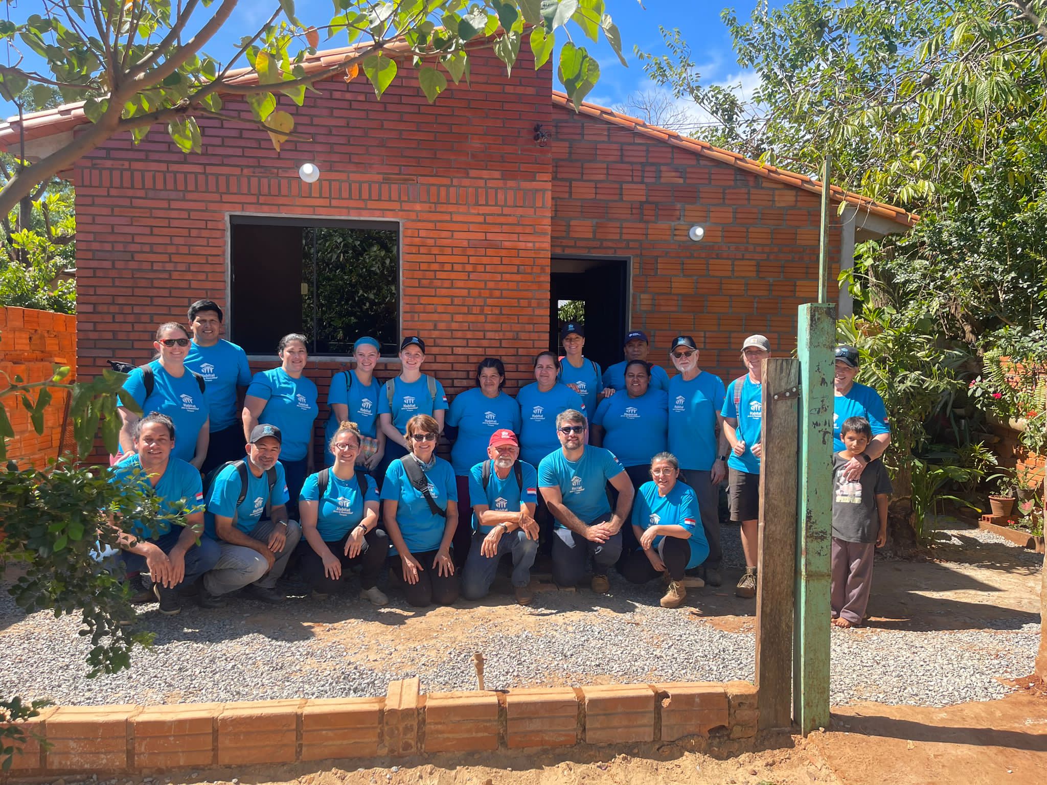 Volunteers pose in front of the home they helped build.