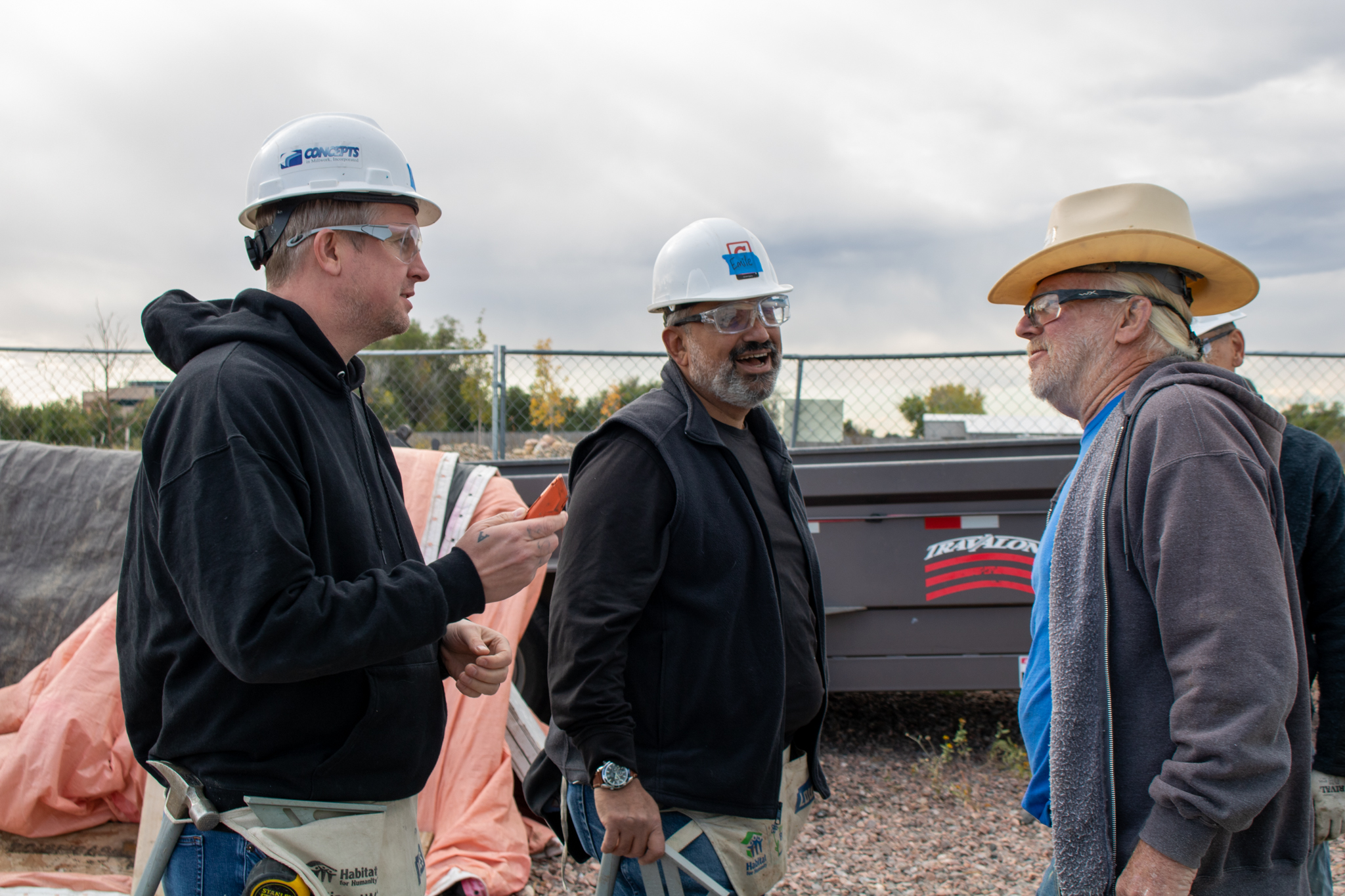 Volunteers in hard hats speaking with construction staff