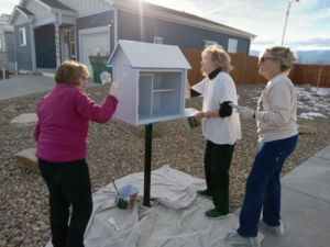 Three women painting the little library
