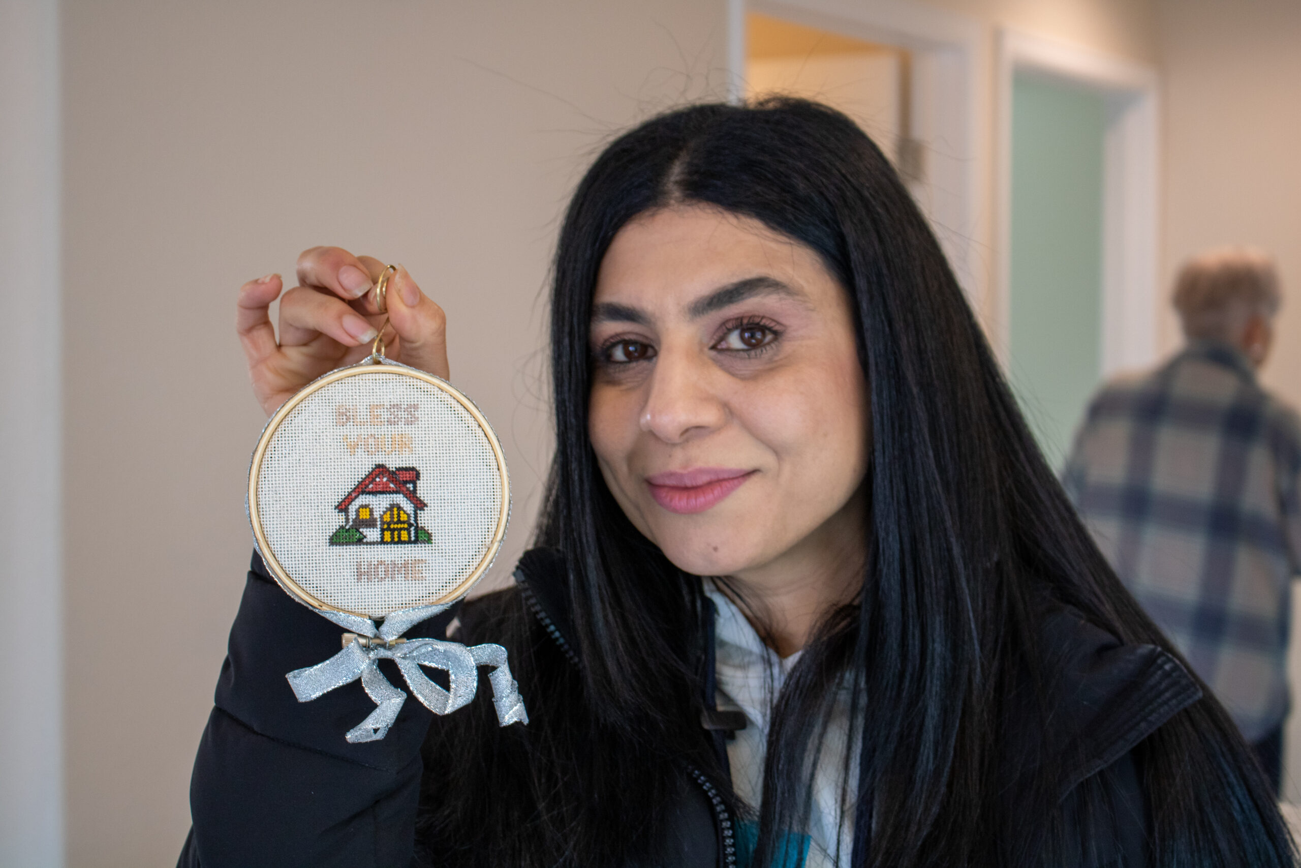 Woman holding cross-stitched ornament showing a house