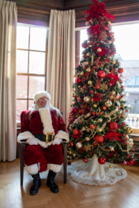 Man in Santa costume seated by Christmas tree