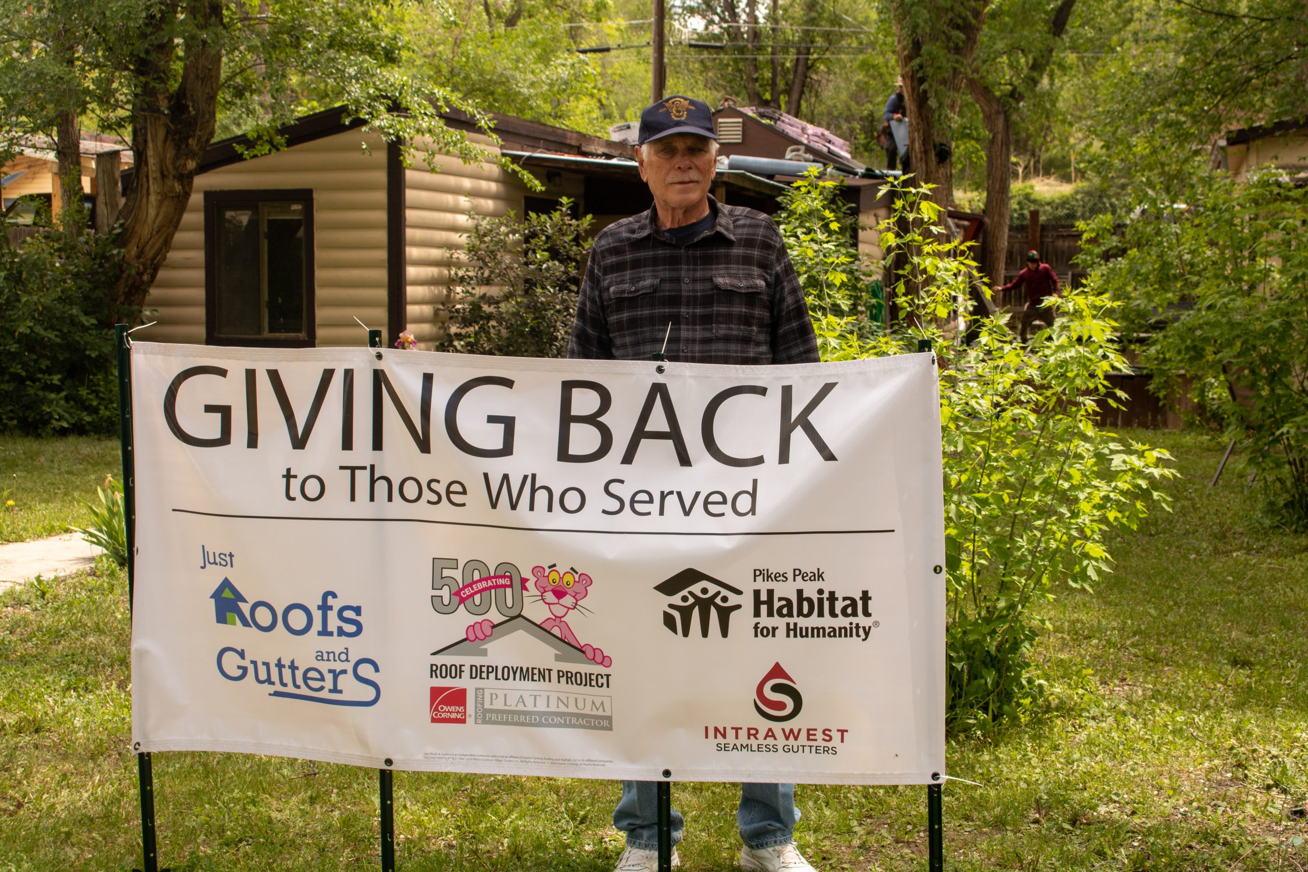 Man standing behind banner that says Giving Back