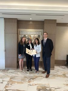 Four people in a lobby holding a plaque