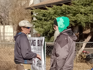 People talking in front of roof donation banner