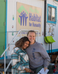 Women embracing in front of the construction trailer