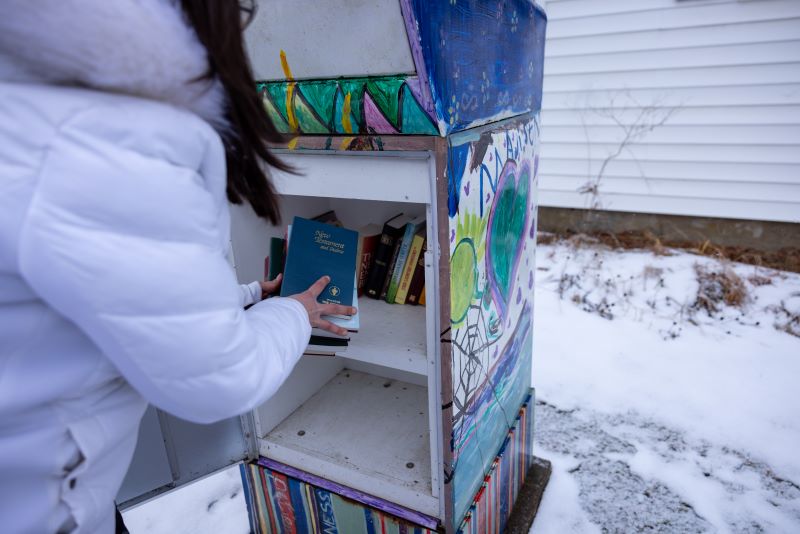 Person putting books into a Little Library