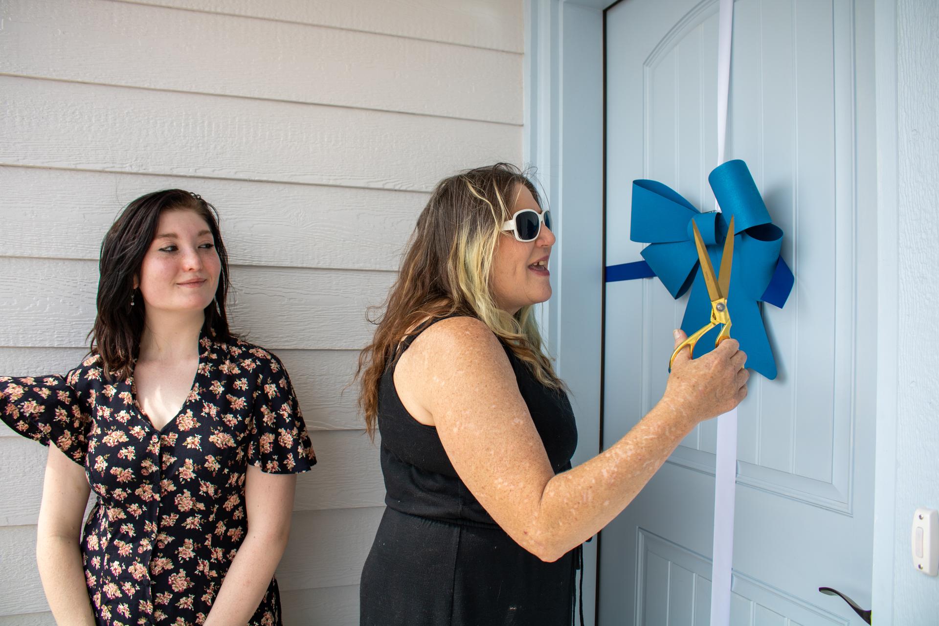 Woman cutting ribbon on her front door