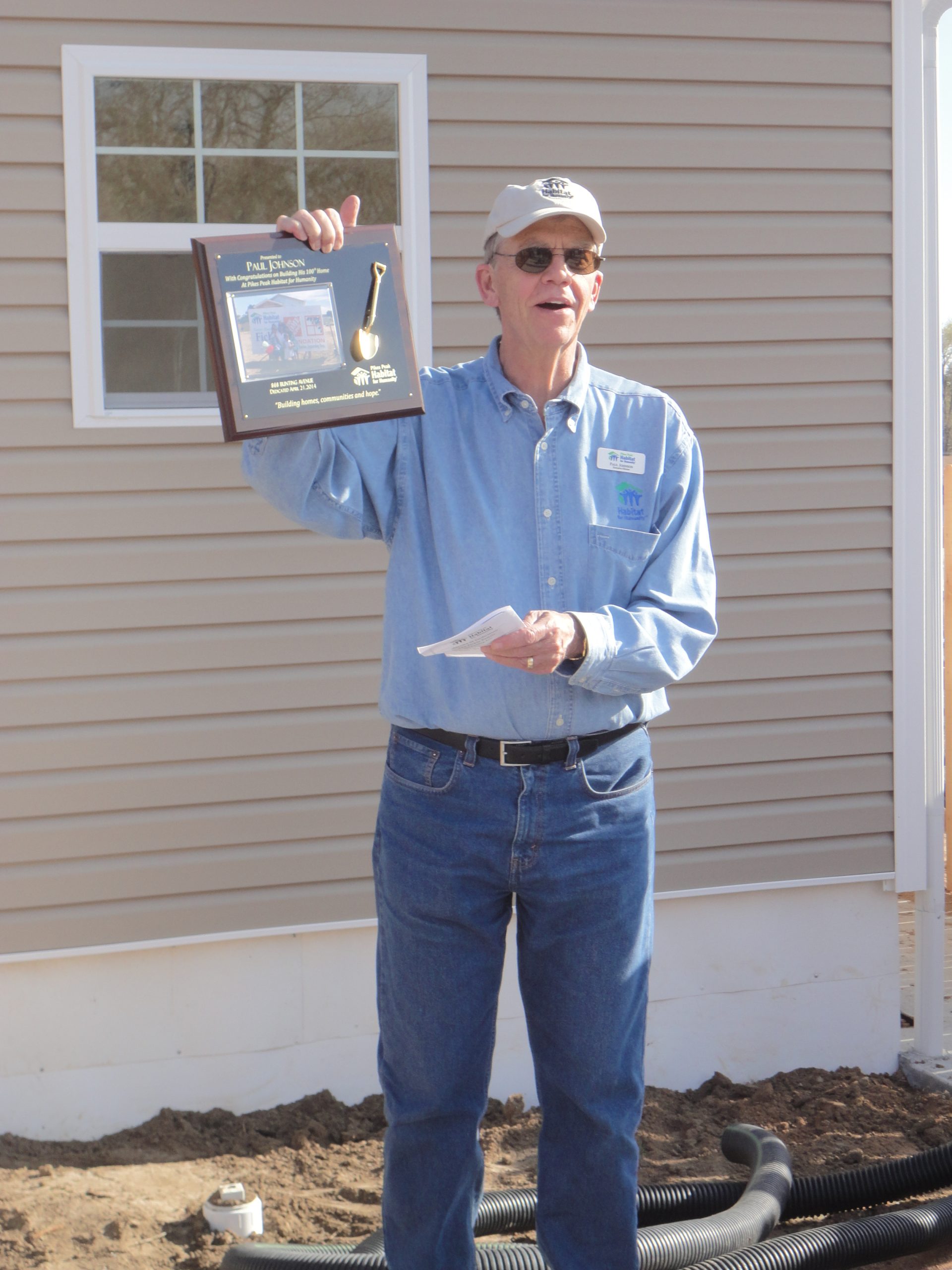 Man holding plaque in front of home