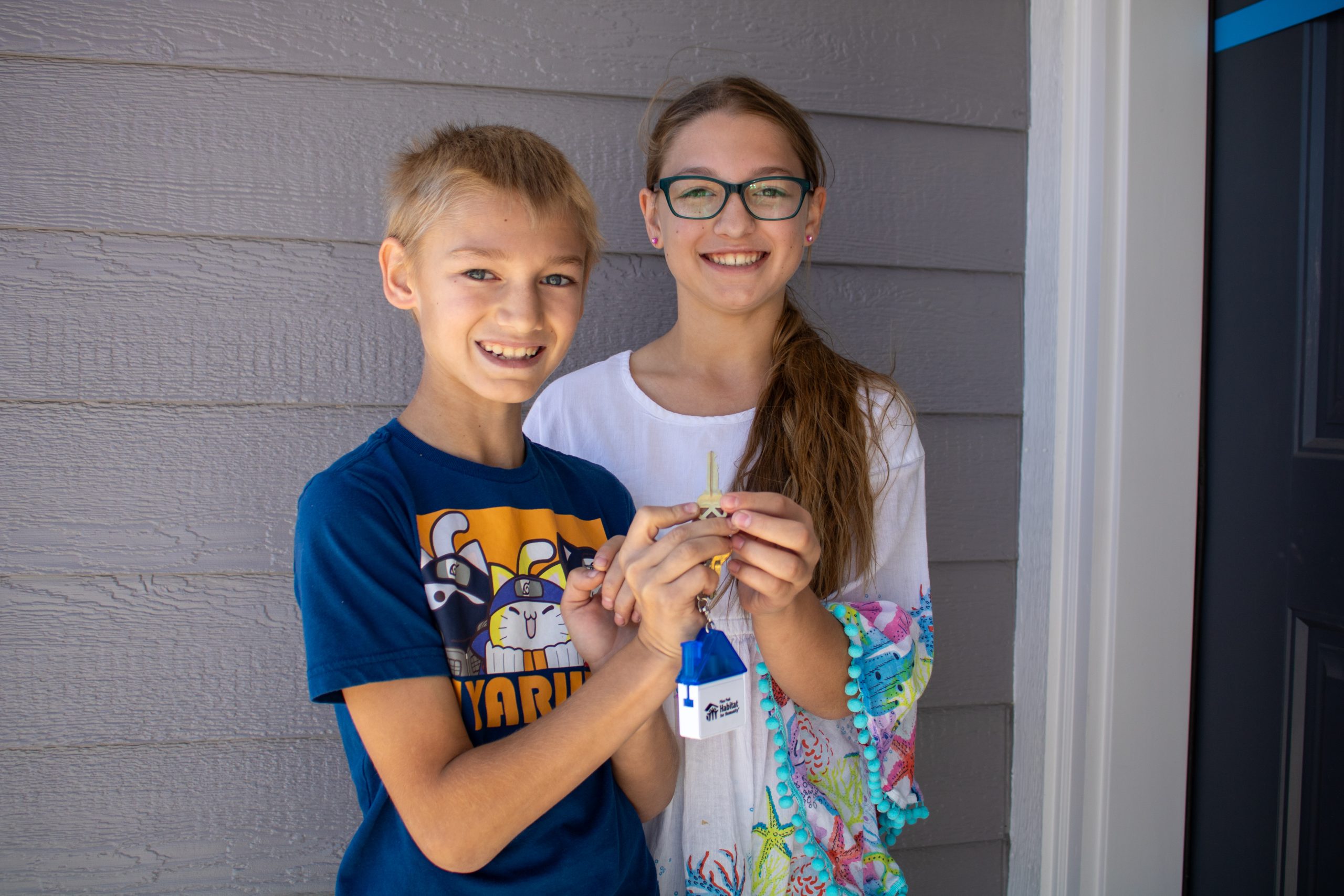 Girl and boy hold keys to their house