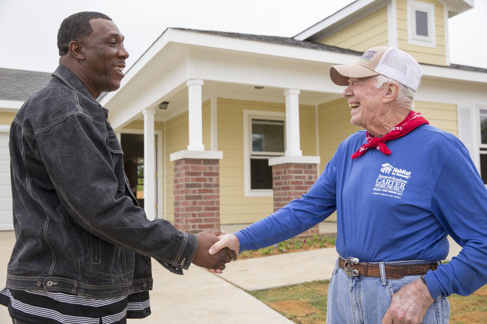 President Carter shaking hands with another man in front of a home